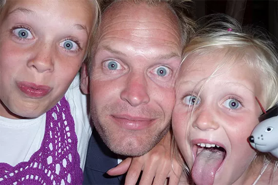 Vater schaut mit seinen beiden Töchtern mit großen Augen in die Kamera